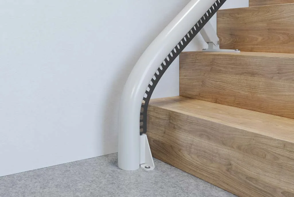 Close-up of the Access Flow X drop nose rail curving down to the floor at the bottom step of a wooden staircase