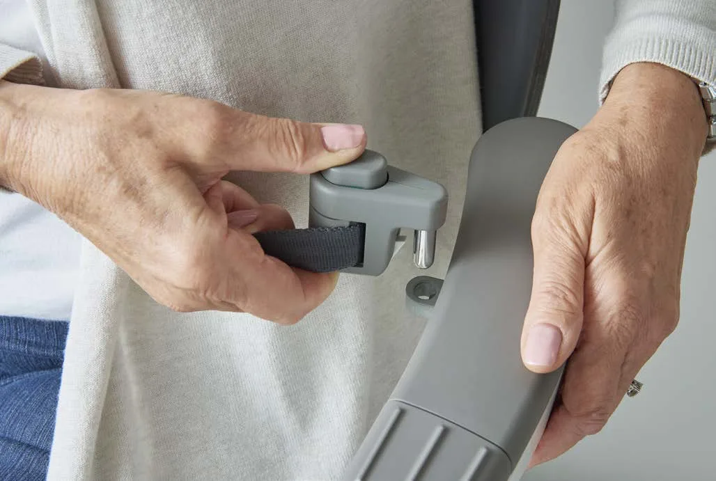 Close-up of two hands fastening the Access Flow X seatbelt one-handed, with the buckle mounted on the armrest