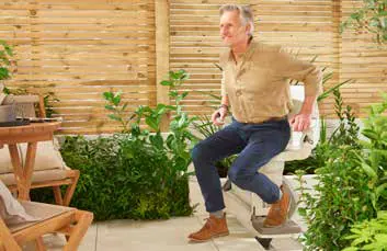 Seated on the chair at patio level, with the molded outdoor seat and folding footrest.