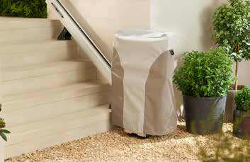 The HomeGlide Outdoor stairlift parked at the bottom of stone steps with its full-length protective cover fitted
