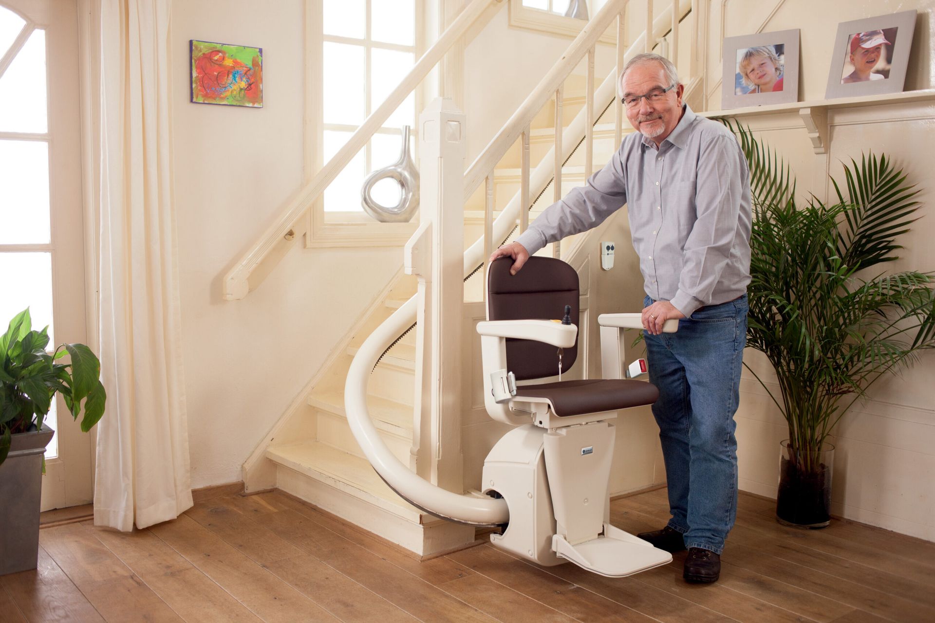 A man at home with a curved stairlift installed on his staircase
