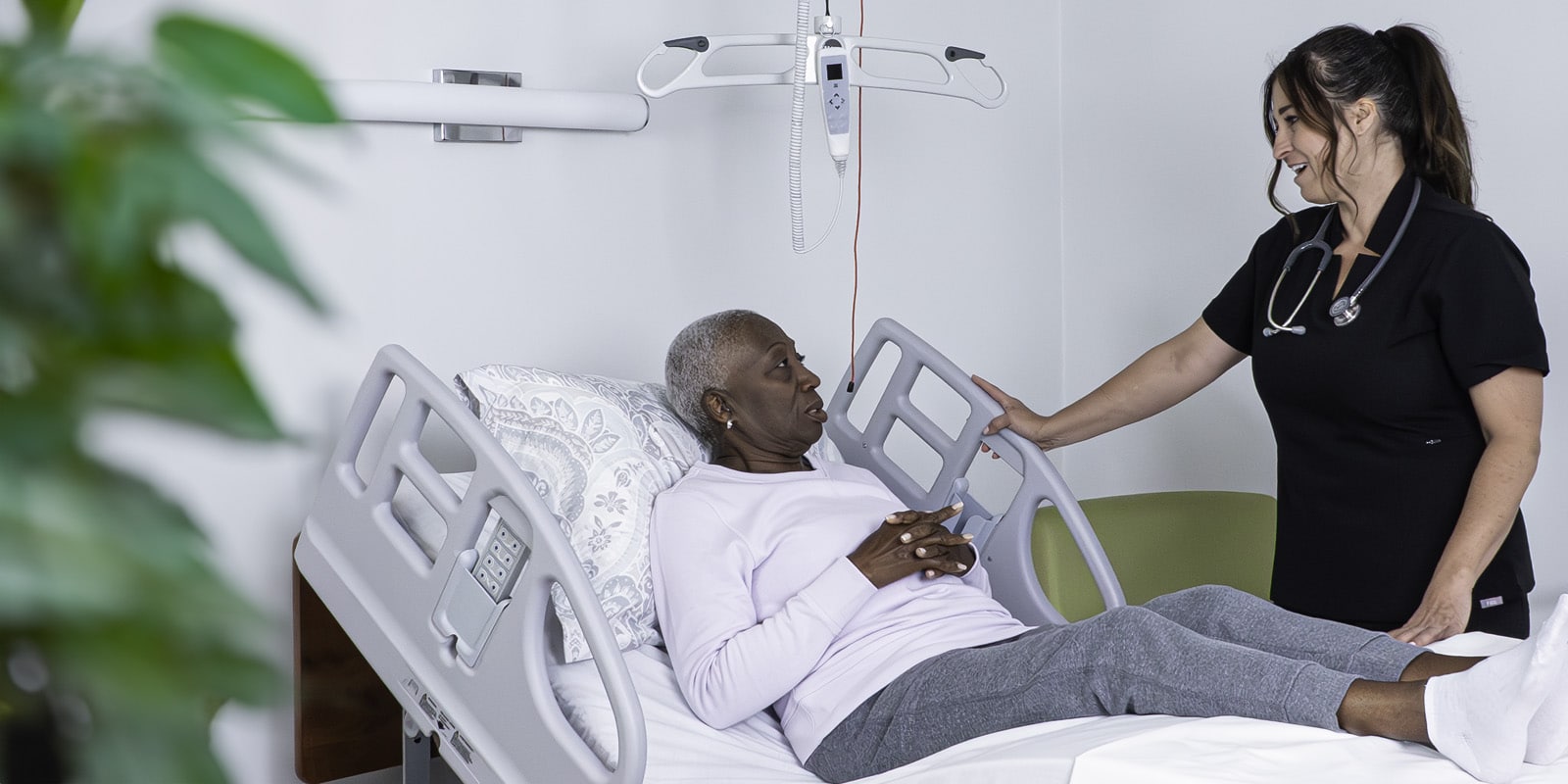 A clinician transferring a patient with a Savaria ceiling lift in a care room
