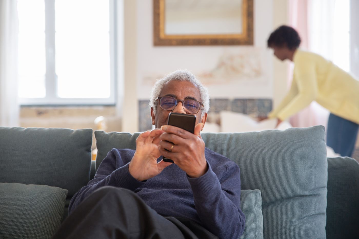 An older man at home booking an assessment on his phone
