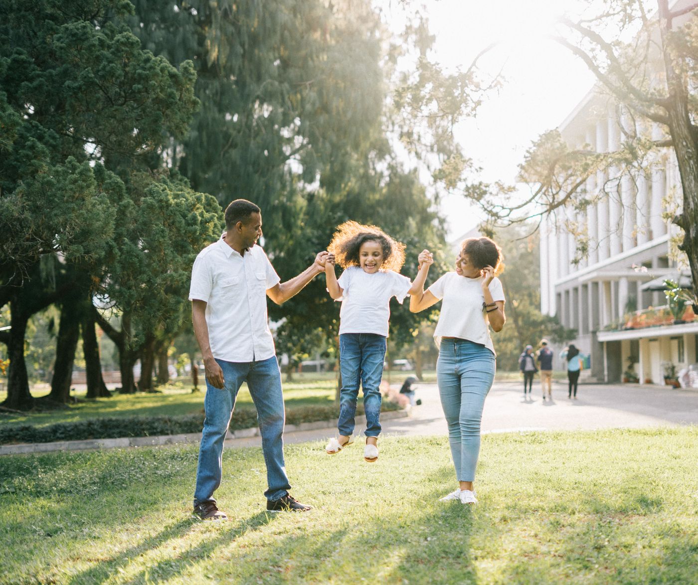 A family holding hands with their daughter in a sunny park