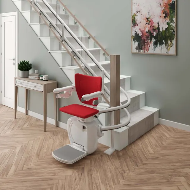 Handicare 4000 with a red seat and white curved rail at the foot of a modern staircase