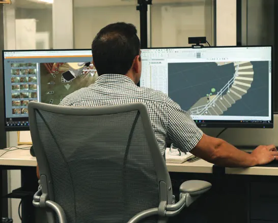 An engineer at a workstation producing a computer-aided drawing of a curved stairlift rail