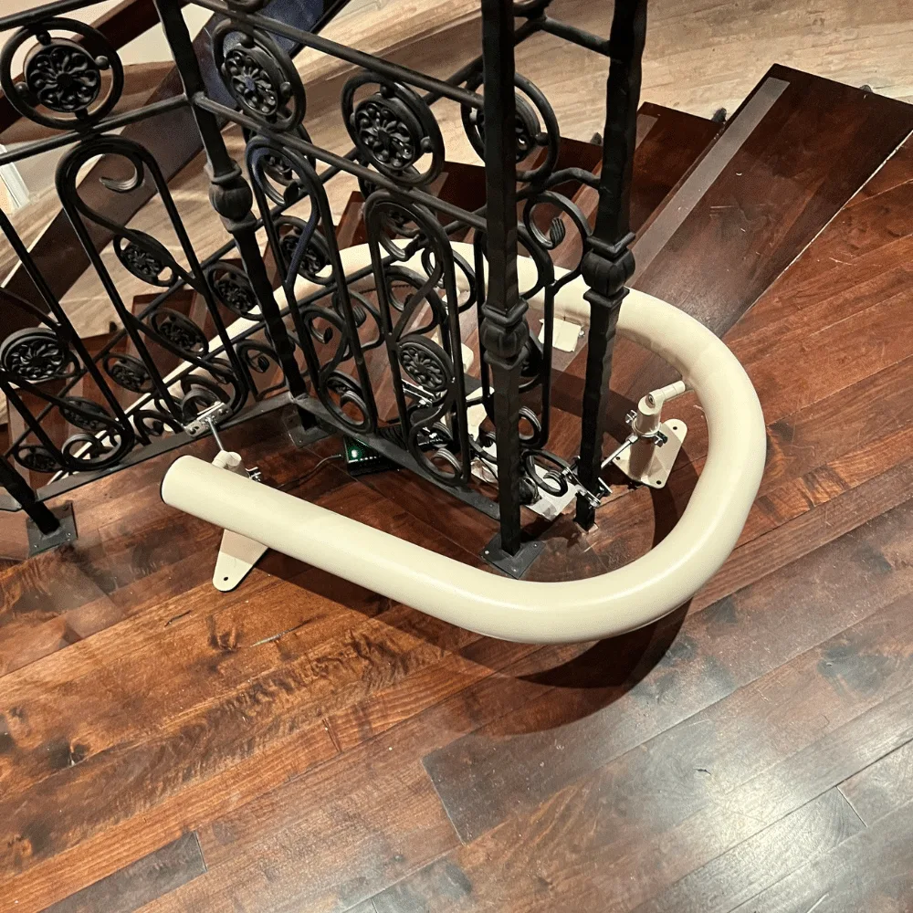 Freecurve rail looping one hundred and eighty degrees at the foot of a staircase with black iron balusters