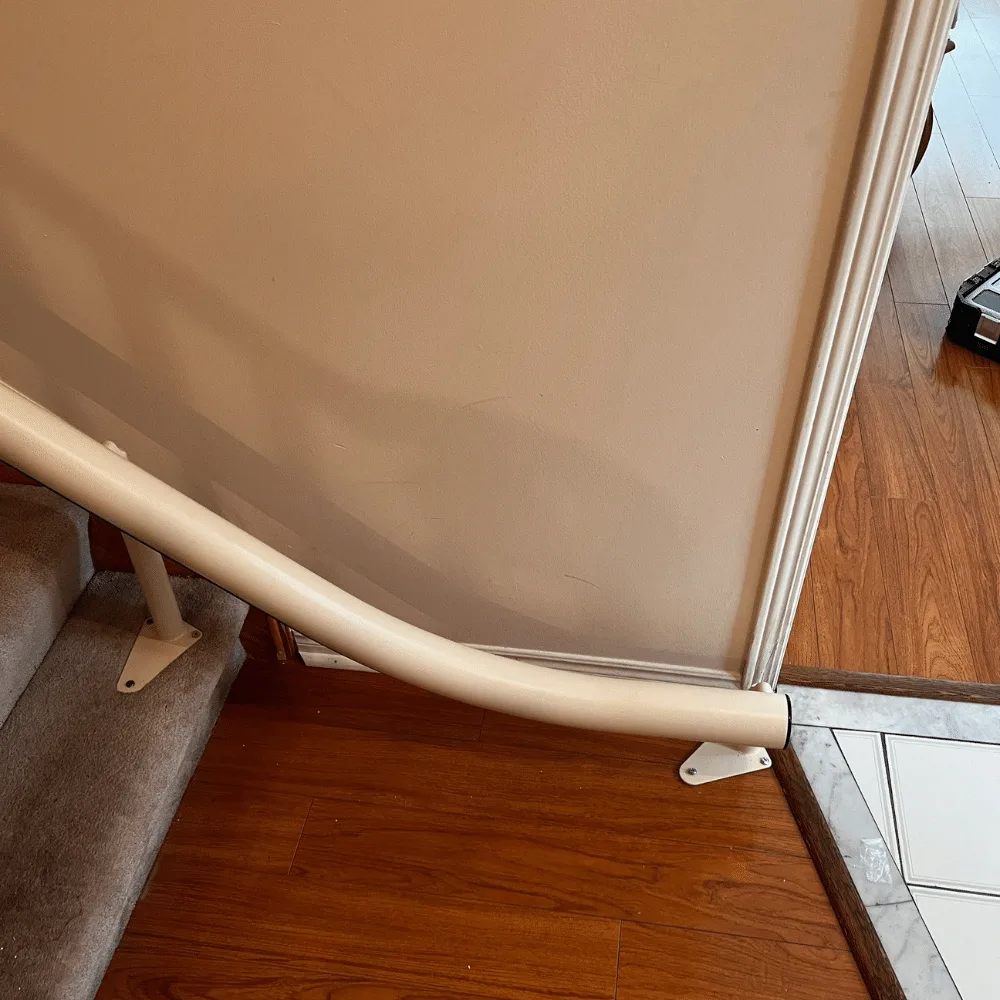 Cream Freecurve rail curving down past the bottom step and finishing flat on a marble tiled floor