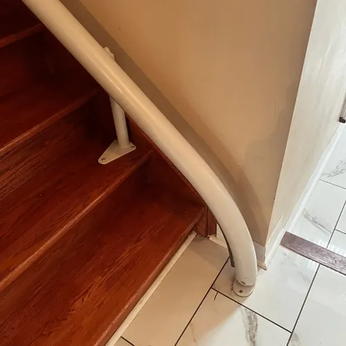 Drop nose rail end curving down to the tiled floor at the bottom step of a staircase