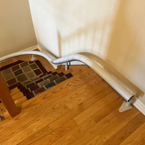 Grey single-tube Freecurve rail curving over the top landing of a staircase and running along the wall