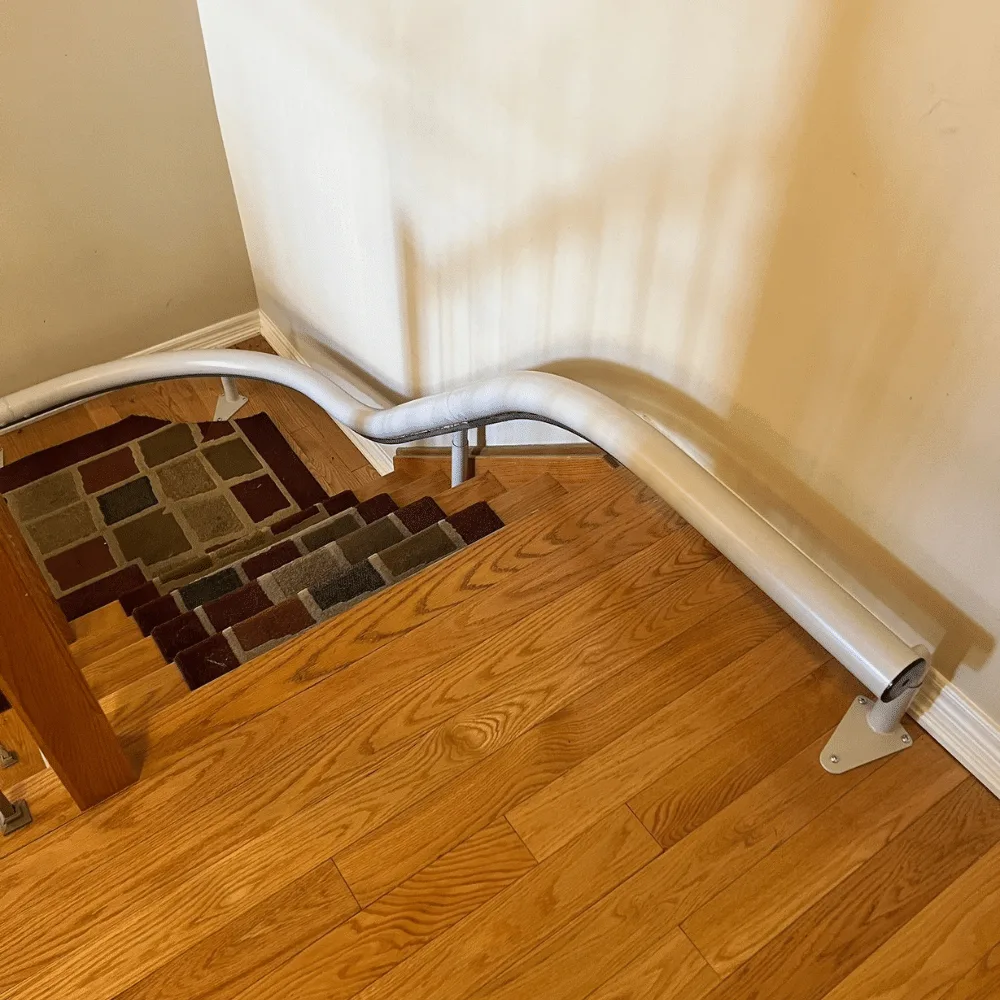 Grey single-tube Freecurve rail curving over the top landing of a staircase and running along the wall