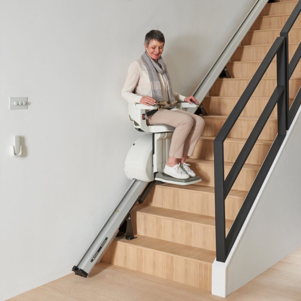 A woman riding a straight indoor stairlift