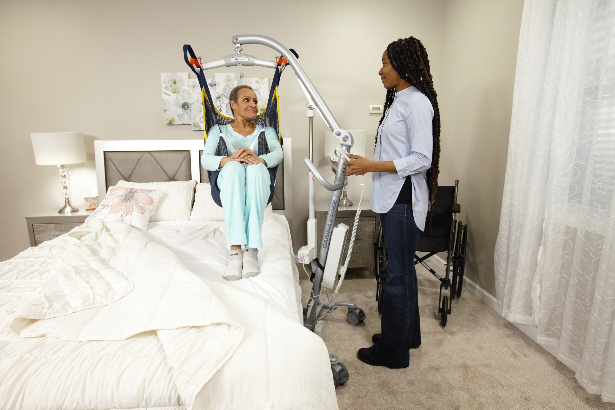 A Carina homecare floor lift beside a bed