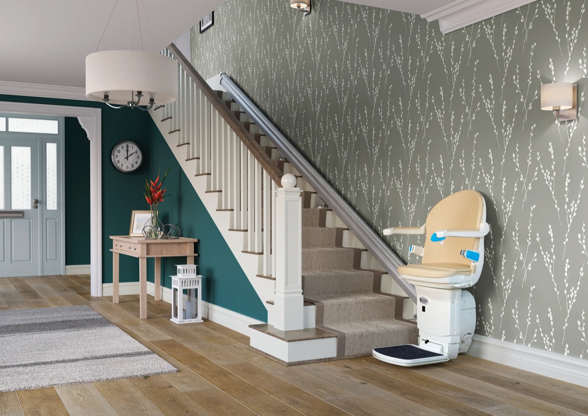 Handicare 1000 stairlift parked at the foot of a straight indoor staircase