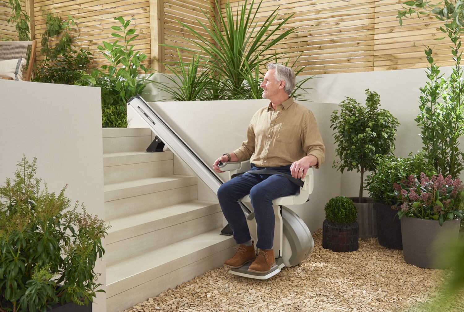 A man riding an outdoor stairlift on garden steps