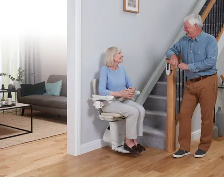 A woman riding a Handicare 1100 while her husband walks beside her